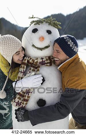 Couple hugging snowman View Large Photo Image Stock Photography - Couple hugging snowman. Fotosearch