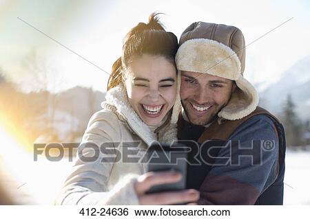 Stock Photograph - Couple taking selfie in snow. Fotosearch