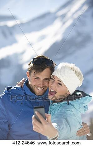 Stock Photograph - Couple taking selfie in snow. Fotosearch