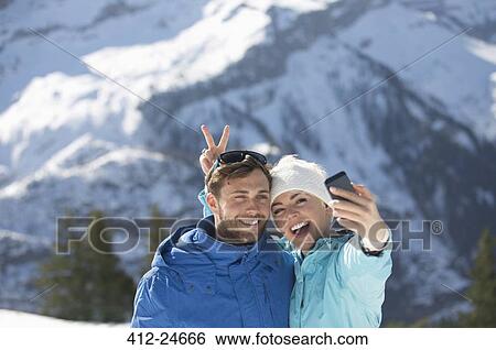 Stock Photograph - Couple taking selfie in snow. Fotosearch