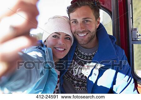 Stock Image - Couple talking selfie in ski lift. Fotosearch