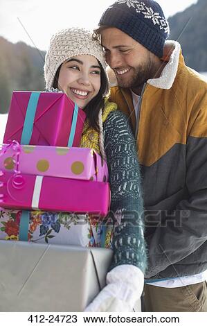 Stock Image - Couple with Christmas gifts in snow. Fotosearch