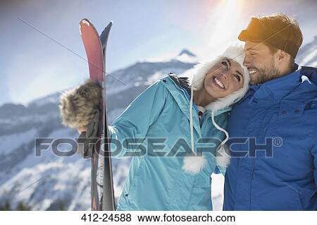 Stock Photo - Couple with skis hugging at mountain. Fotosearch