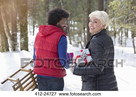 Couple with sled and Christmas gifts in snow View Large Photo Image Stock Photo - Couple with sled and Christmas gifts in snow. Fotosearch