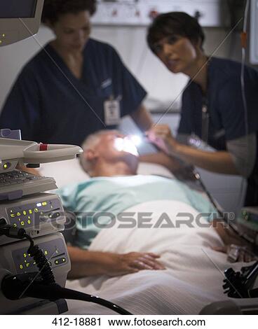 Doctor examining senior patient with flashlight in intensive care unit View Large Photo Image Stock Image - Doctor examining senior patient with flashlight in intensive care unit. Fotosearch