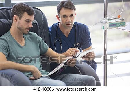 Stock Photography - Doctor holding digital tablet, talking to patient undergoing medical treatment in hospital. Fotosearch
