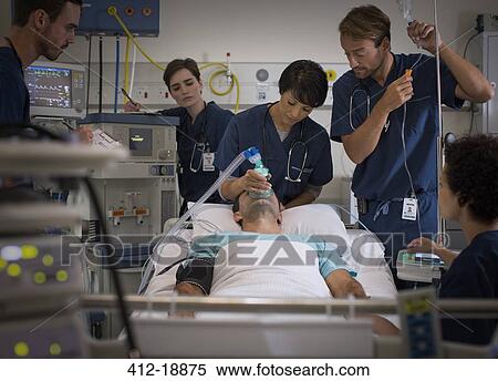 Doctor holding mask over patient's mouth and doctor controlling IV drip in intensive care unit View Large Photo Image Stock Photography - Doctor holding mask over patient's mouth and doctor controlling IV drip in intensive care unit. Fotosearch