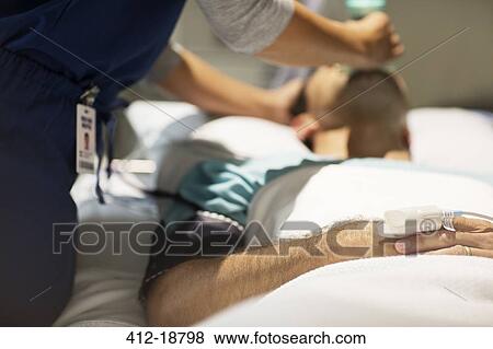 Doctor holding oxygen mask over male patient's mouth in intensive care unit View Large Photo Image Stock Photo - Doctor holding oxygen mask over male patient's mouth in intensive care unit. Fotosearch