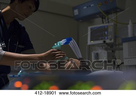 Doctor holding oxygen mask over patient's face in intensive care unit View Large Photo Image Stock Image - Doctor holding oxygen mask over patient's face in intensive care unit. Fotosearch