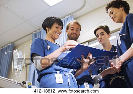 Doctors wearing scrubs, looking at documents in hospital ward View Large Photo Image Stock Image - Doctors wearing scrubs, looking at documents in hospital ward. Fotosearch
