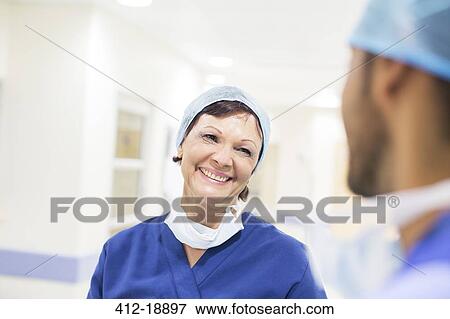 Stock Photo - Doctors wearing surgical caps standing in hospital corridor and talking. Fotosearch