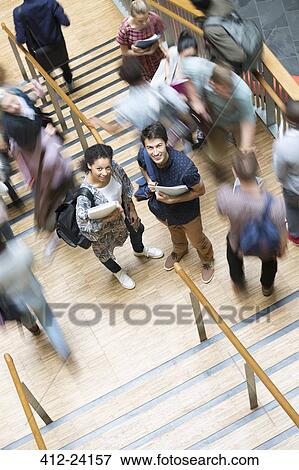 Elevated view of two smiling students standing on stairs with other students going up and down View Large Photo Image Stock Photo - Elevated view of two smiling students standing on stairs with other students going up and down. Fotosearch