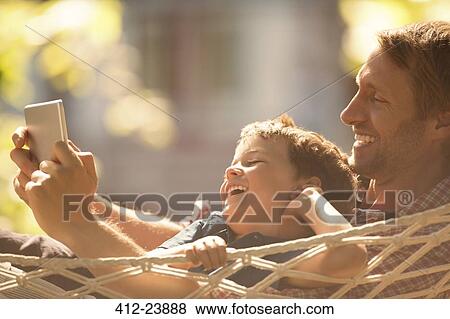 Father and son using digital tablet in hammock View Large Photo Image Stock Photo - Father and son using digital tablet in hammock. Fotosearch