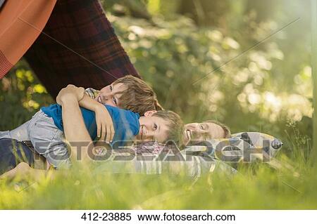 Stock Photography - Father and sons relaxing together near camping tent. Fotosearch
