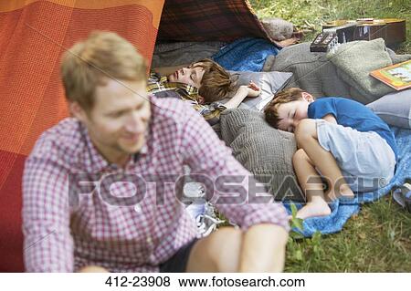 Father sitting with sleeping sons at camping tent View Large Photo Image Stock Photo - Father sitting with sleeping sons at camping tent. Fotosearch