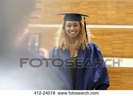 Stock Photo - Female student in graduation gown posing for picture in university corridor. Fotosearch