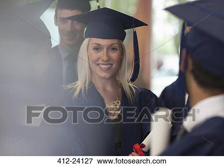 Stock Photo - Female student smiling in graduation clothes surrounded by other students. Fotosearch