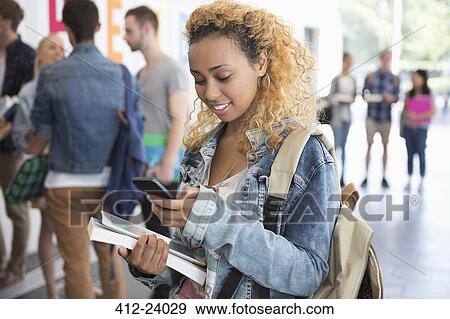 Stock Photo - Female student standing in corridor and texting. Fotosearch