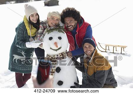 Friends around snowman View Large Photo Image Stock Photo - Friends around snowman. Fotosearch