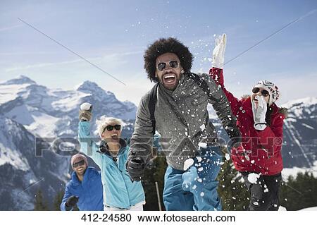 Stock Image - Friends enjoying snowball fight at mountain. Fotosearch