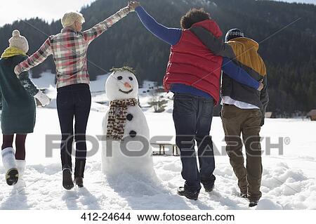 Friends playing around snowman View Large Photo Image Picture - Friends playing around snowman. Fotosearch