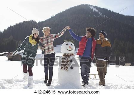 Friends playing around snowman View Large Photo Image Stock Photography - Friends playing around snowman. Fotosearch