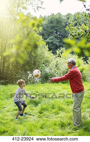 Picture - Grandfather and grandson playing soccer in grass. Fotosearch