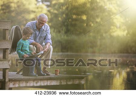 Grandfather and grandson reading at lake View Large Photo Image Stock Photograph - Grandfather and grandson reading at lake. Fotosearch
