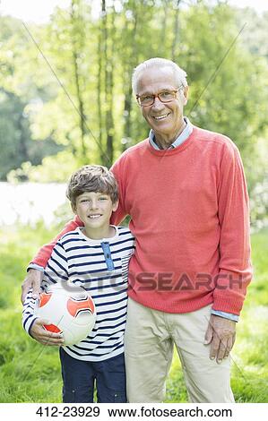 Stock Photo - Grandfather and grandson smiling outdoors with soccer ball. Fotosearch