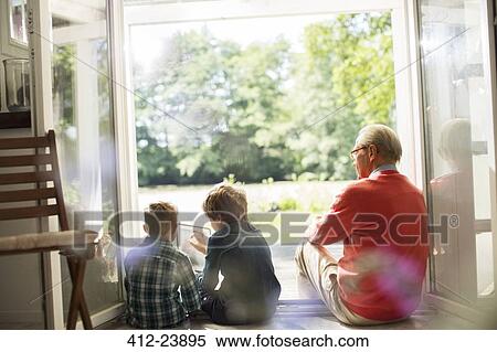 Stock Photography - Grandfather and grandsons relaxing in doorway. Fotosearch
