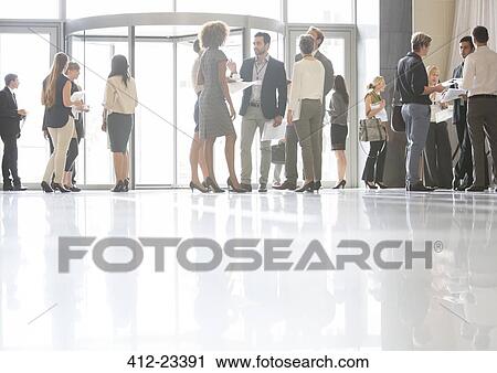 Stock Image - Group of business people standing and talking in office. Fotosearch