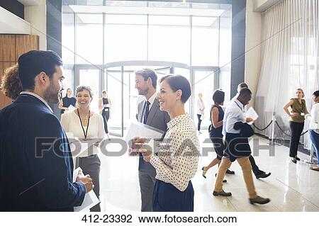 Stock Image - Group of business people standing and talking in office. Fotosearch