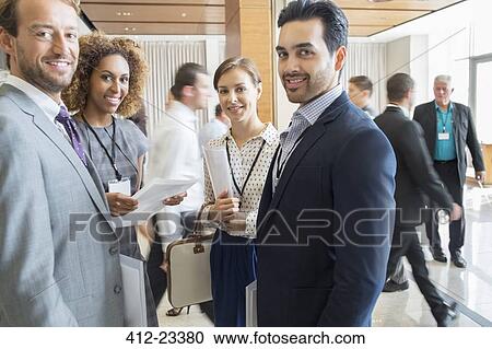 Stock Image - Group of business people standing in office hall, smiling and looking at camera. Fotosearch