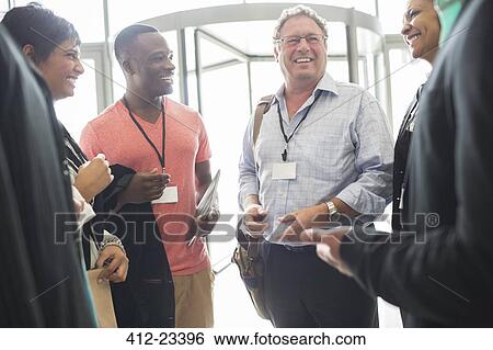 Stock Photograph - Group of business people standing in office hall, talking and smiling. Fotosearch