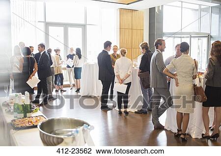 Stock Image - Group of conference participants standing in lobby of conference center, socializing during lunch break. Fotosearch