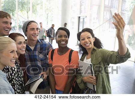 Picture - Group of smiling students holding books and digital tablet, taking selfie with smart phone. Fotosearch