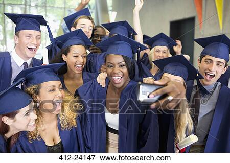 Stock Photo - Group of smiling students in graduation gowns taking selfie on graduation day. Fotosearch