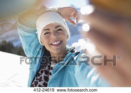Stock Photo - Happy woman taking selfie in snow. Fotosearch