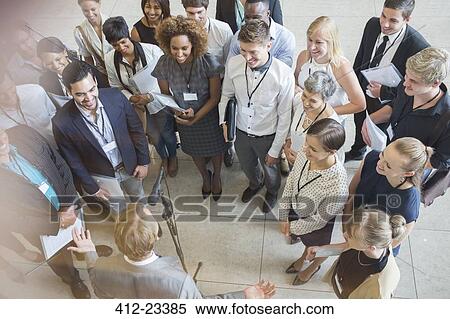 Stock Photography - High angle view of business people looking at colleague giving speech. Fotosearch