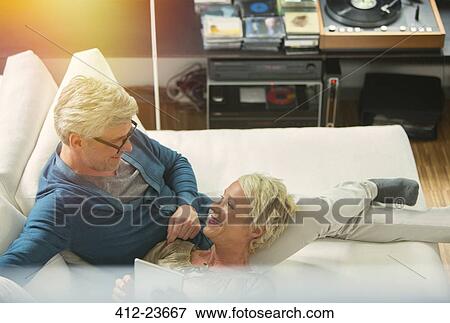 Stock Photo - High angle view of older couple relaxing together on living room sofa. Fotosearch