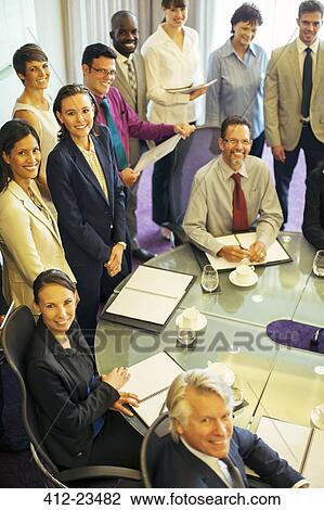 High angle view of smiling business people looking at camera in conference room View Large Photo Image Stock Image - High angle view of smiling business people looking at camera in conference room. Fotosearch