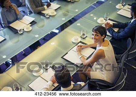 High angle view of smiling businesswoman looking at camera and sitting in conference room View Large Photo Image Stock Photograph - High angle view of smiling businesswoman looking at camera and sitting in conference room. Fotosearch