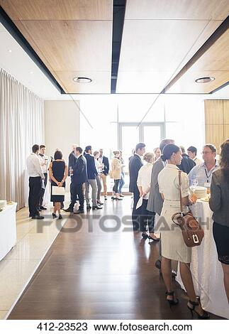 Stock Image - Large group of people socializing in lobby of conference center during coffee break. Fotosearch