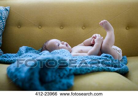 Little baby lying on blue cloth with legs raised, holding one foot View Large Photo Image Stock Photograph - Little baby lying on blue cloth with legs raised, holding one foot. Fotosearch