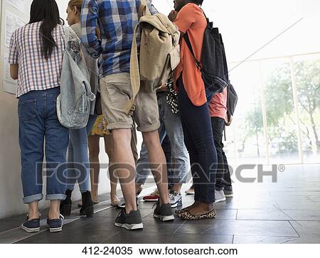 Stock Photography - Low-angle view of university students standing in corridor and looking at test results. Fotosearch
