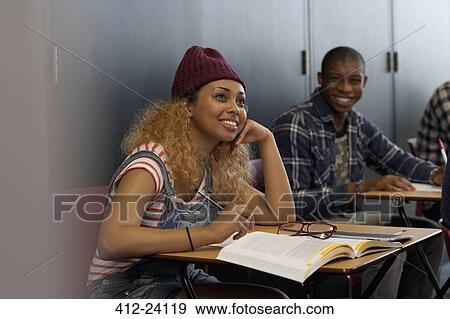Stock Photo - Male and female students smiling sitting at desks during lecture. Fotosearch