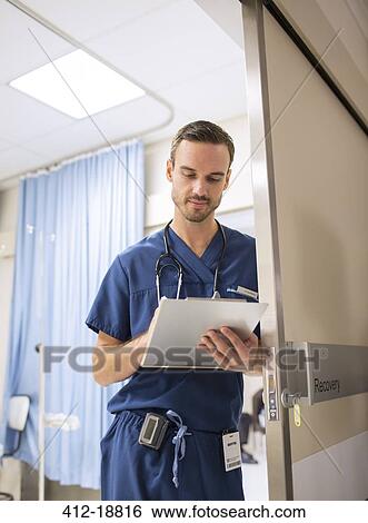 Male doctor standing in doorway, taking notes on clip board in hospital View Large Photo Image Stock Photograph - Male doctor standing in doorway, taking notes on clip board in hospital. Fotosearch