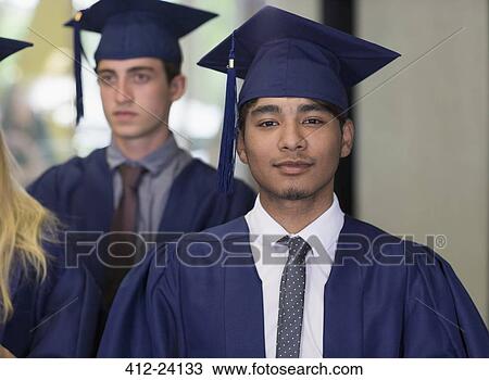 Stock Image - Male student in graduation clothes looking at camera. Fotosearch