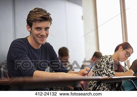 Male student smiling at camera and sitting at desk during lecture View Large Photo Image Stock Image - Male student smiling at camera and sitting at desk during lecture. Fotosearch