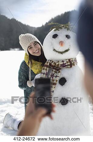 Man photographing woman with snowman View Large Photo Image Stock Image - Man photographing woman with snowman. Fotosearch
